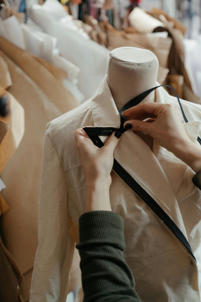 pexels-photo-4622423-4622423 Close-up of tailor adjusting a garment on a mannequin, symbolizing fashion design in a creative studio.