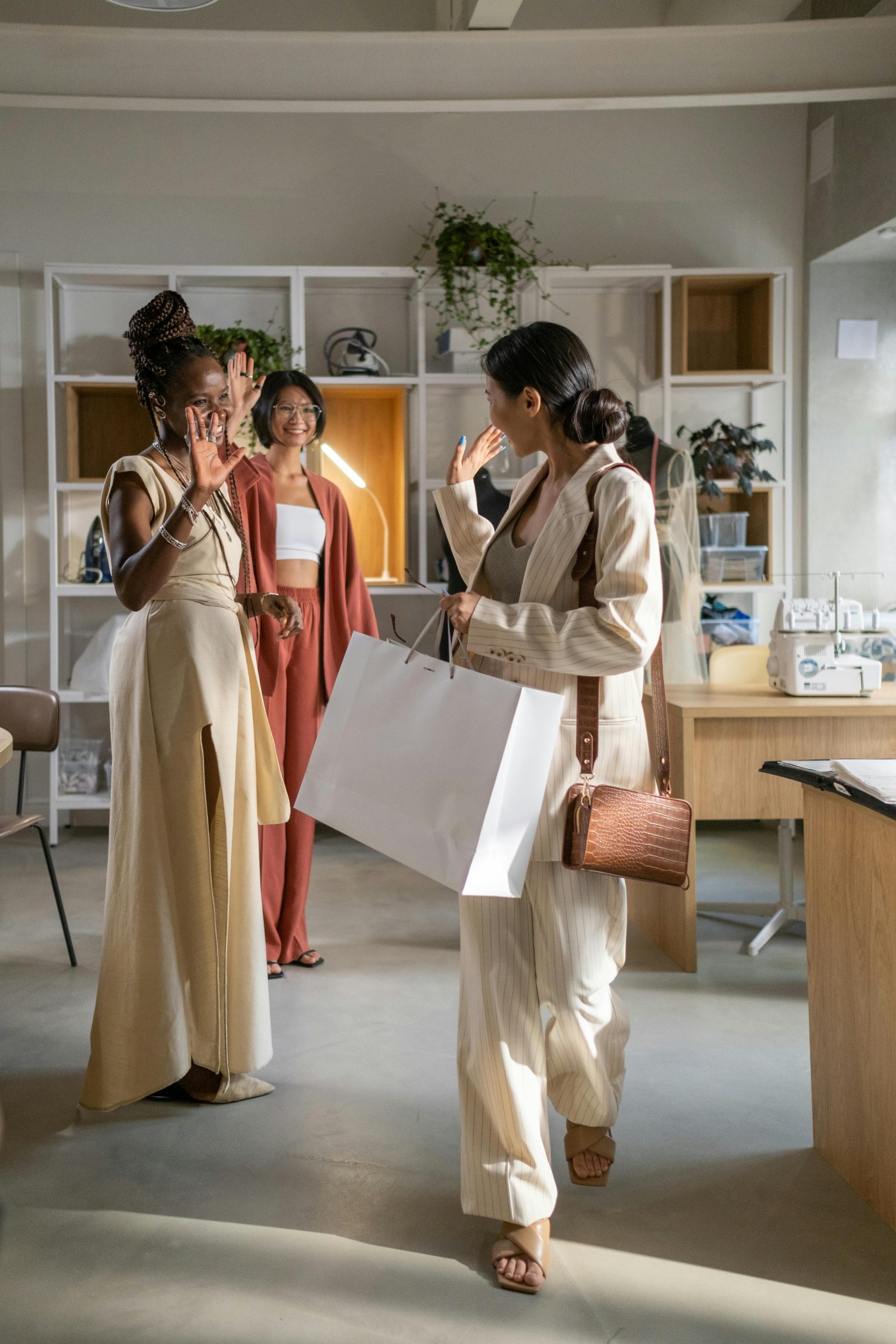 Three women enjoying a shopping experience in a stylish fashion studio.